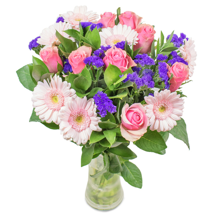 Set against a crisp white background, this vibrant bouquet-arranged by a seasoned Peckham florist-features approximately eight pastel to medium pink roses at varying stages of bloom, each spiral centre promising classic romance and warmth. Intertwined are five or six gentle pink gerbera daisies, notable for their generous, rounded petals and luminous, almost white centres, lending the arrangement a radiant focal point. Between these primary blooms, clusters of vivid purple statice or limonium infuse depth and dimension, evoking the creative spirit found throughout Peckham's local art scene. The overall bouquet is anchored by abundant deep green foliage, evoking the freshness of historical green spaces such as Peckham Rye. Stems are arranged visibly in a clear glass vase with fresh water, bringing a sense of lightness and transparency-a nod to the honesty and cheer of local craftsmanship. Designed for special occasions like birthdays, anniversaries, or just to bring a touch of Peckham joy home, this bouquet conveys a message of affection and joyful celebration, crafted to illuminate any setting.